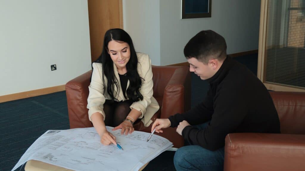 a woman and a man looking at blue print plans for an electric diversion